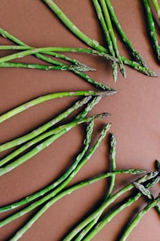Top view of fresh green asparagus arranged on a brown surface.