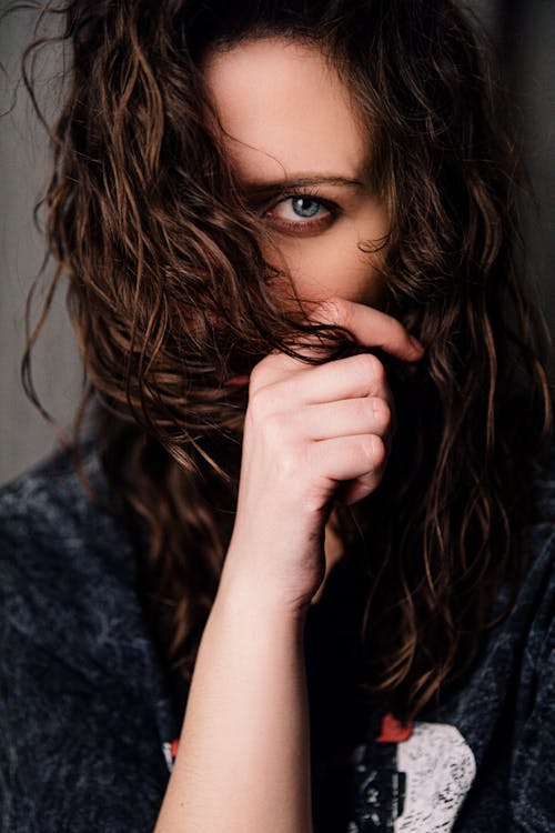 Calm woman covering face with curly hair