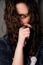 Calm woman covering face with curly hair