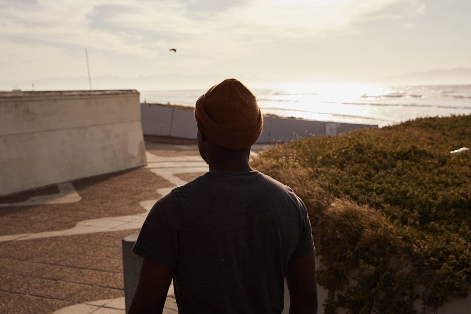 A man in casual attire enjoys a serene view of the ocean on a sunny day.