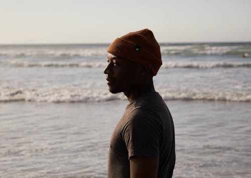 grátis Turista Negro Sonhador Com Chapéu De Malha Perto Do Oceano Foto profissional
