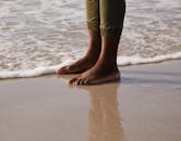 作物匿名民族游客在暴风雨天气中在泡沫海附近的沙滩上反射