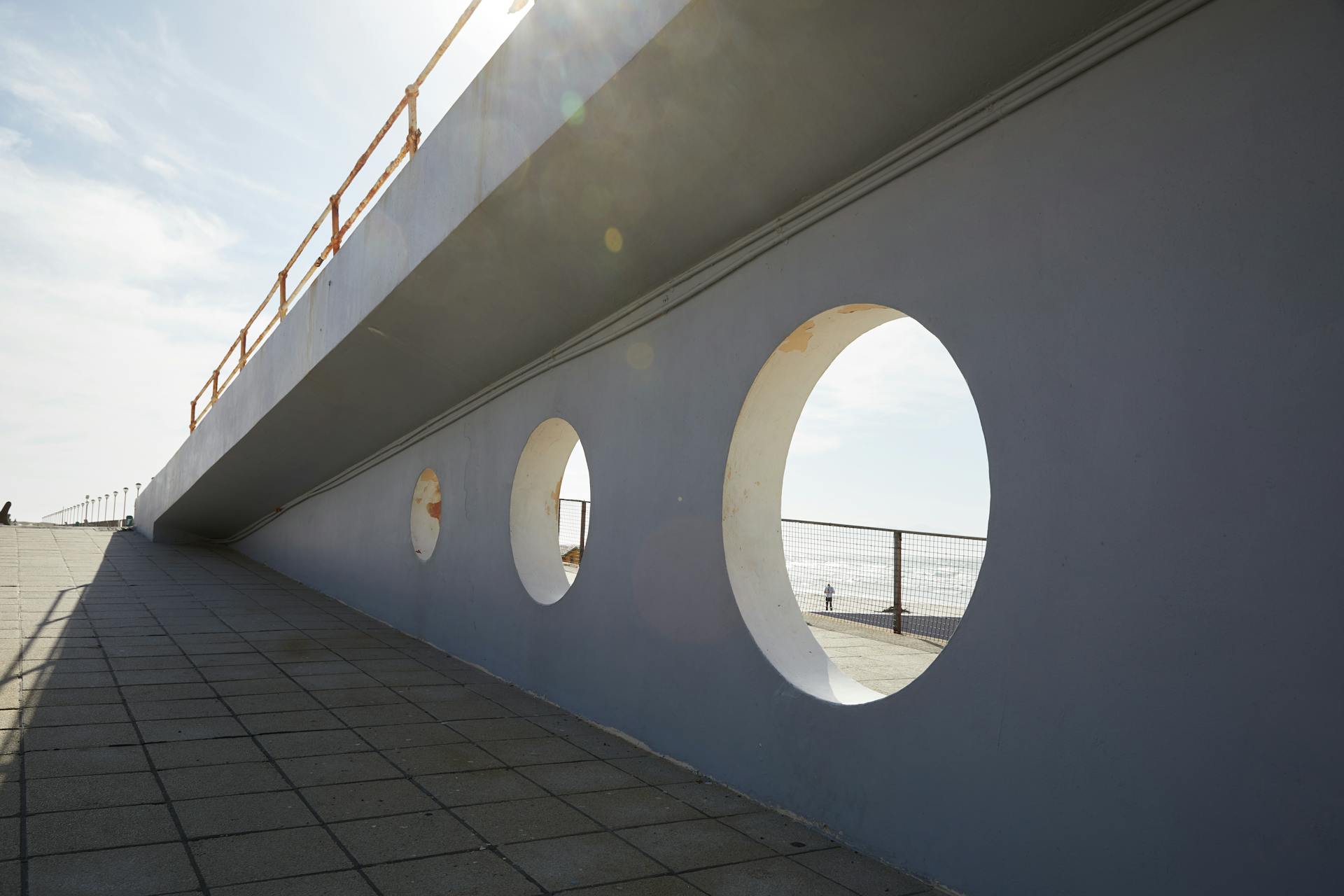 A serene urban scene highlighting modern architecture with circular elements under a bright sky.