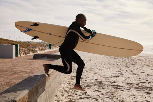 Free Black surfer running to ocean with surfboard in daytime Stock Photo