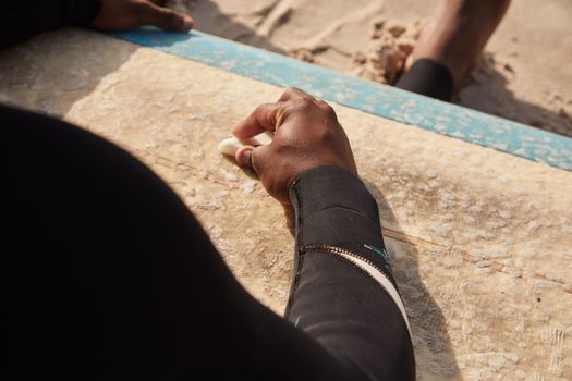 Back view of crop anonymous barefoot African American male preparing for surfing on sunny beach