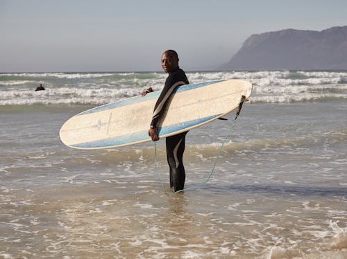 Black man with surfboard on beach · Free Stock Photo