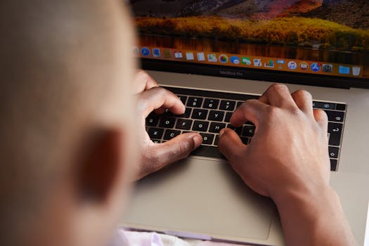 From above of crop anonymous busy African American male typing on keyboard of contemporary netbook