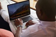 Black man with smart watch using touchpad of laptop