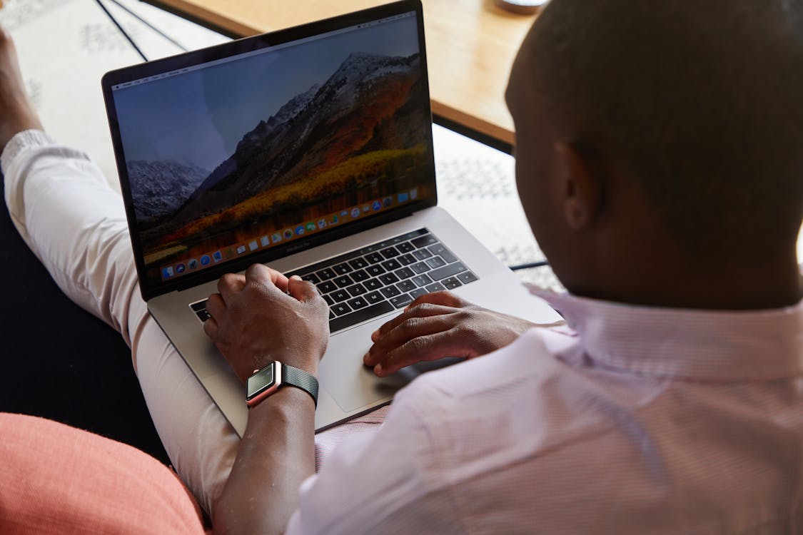 Free Black man with smart watch using touchpad of laptop Stock Photo