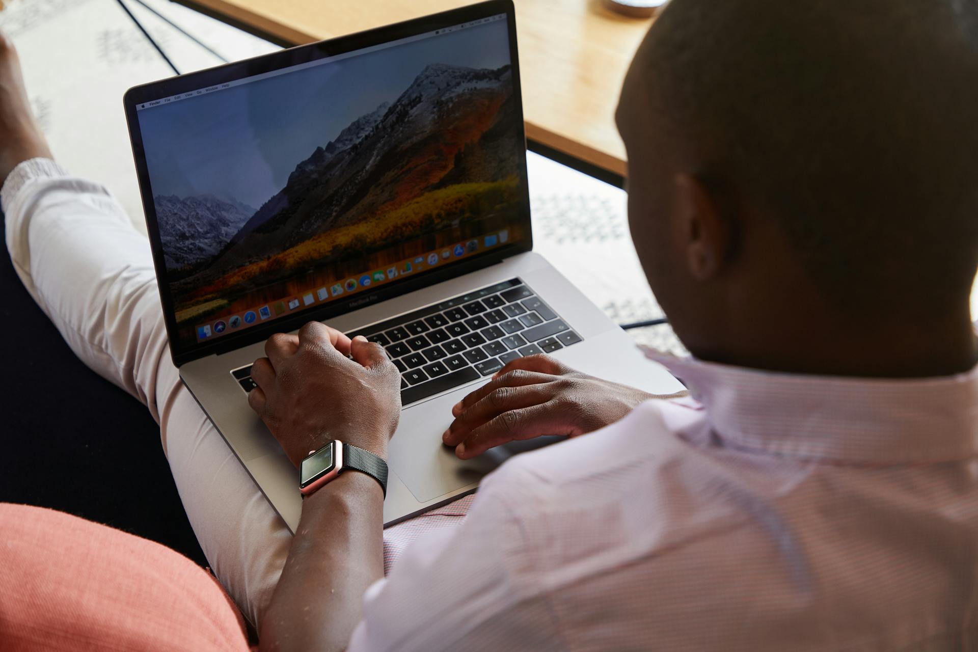 African American man working on a laptop indoors, showcasing concentration and modern technology.