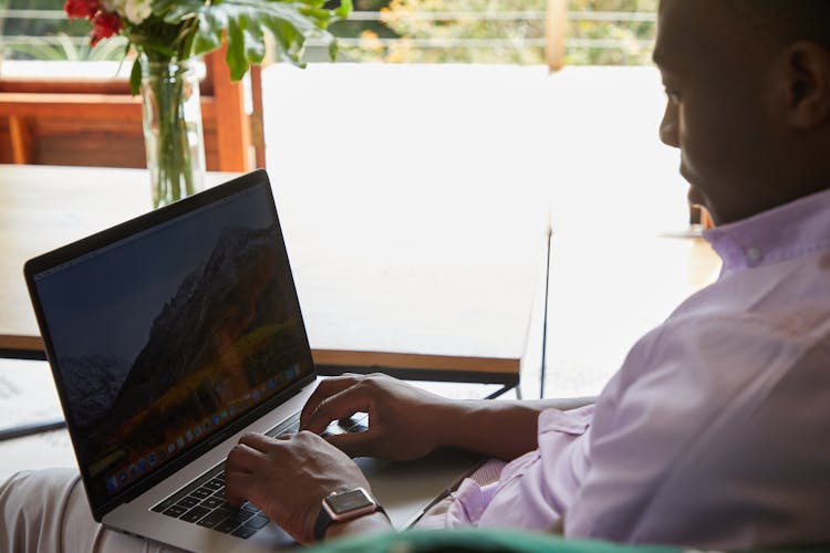 Black Man With Smart Watch Browsing Laptop