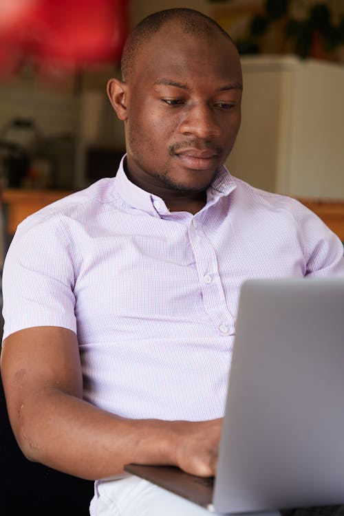 Serious African American male working with project on netbook on blurred background of room