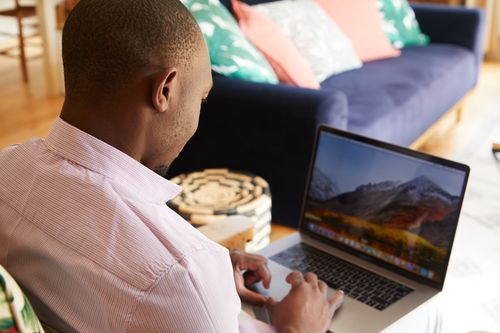 Free Back view of anonymous African American male watching at bright desktop of netbook in comfortable living room Stock Photo