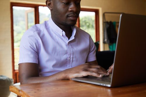 Free Serious African American male in shirt receiving data through internet in netbook in living room Stock Photo