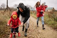 一家人穿着充满活力的服装，在乡村土路上欢乐地享受秋季漫步