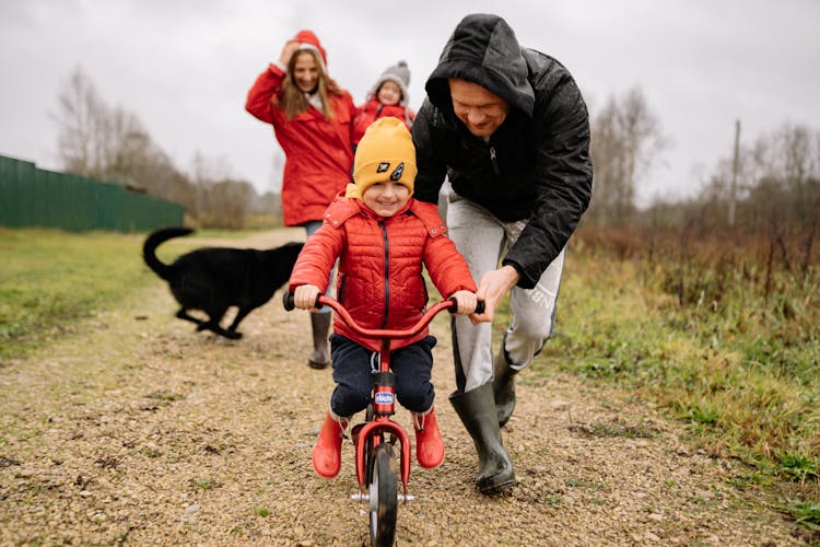 A Father Helping His Child Ride A Bike