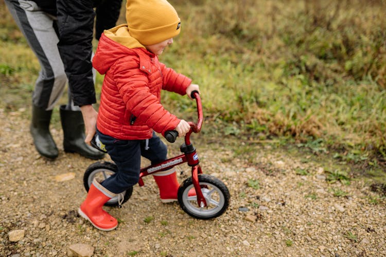 A Child Wearing A Red Jacket Riding A Bike