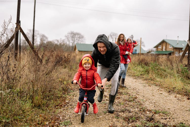 A Father Pushing His Child Riding A Bike