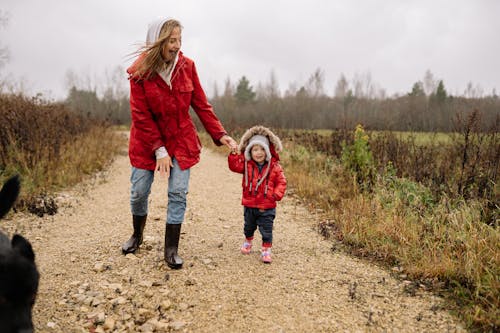 Mother and Child Wearing Red Jackets Walking while Holding Hands