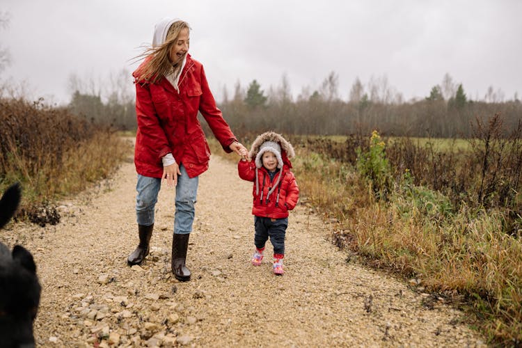 Mother And Child Wearing Red Jackets Walking While Holding Hands