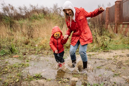 A cheerful mother and child splash in a puddle on a rainy day, both wearing red jackets.