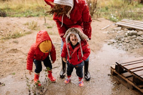 A Mother and Her Children Jumping on a Puddle