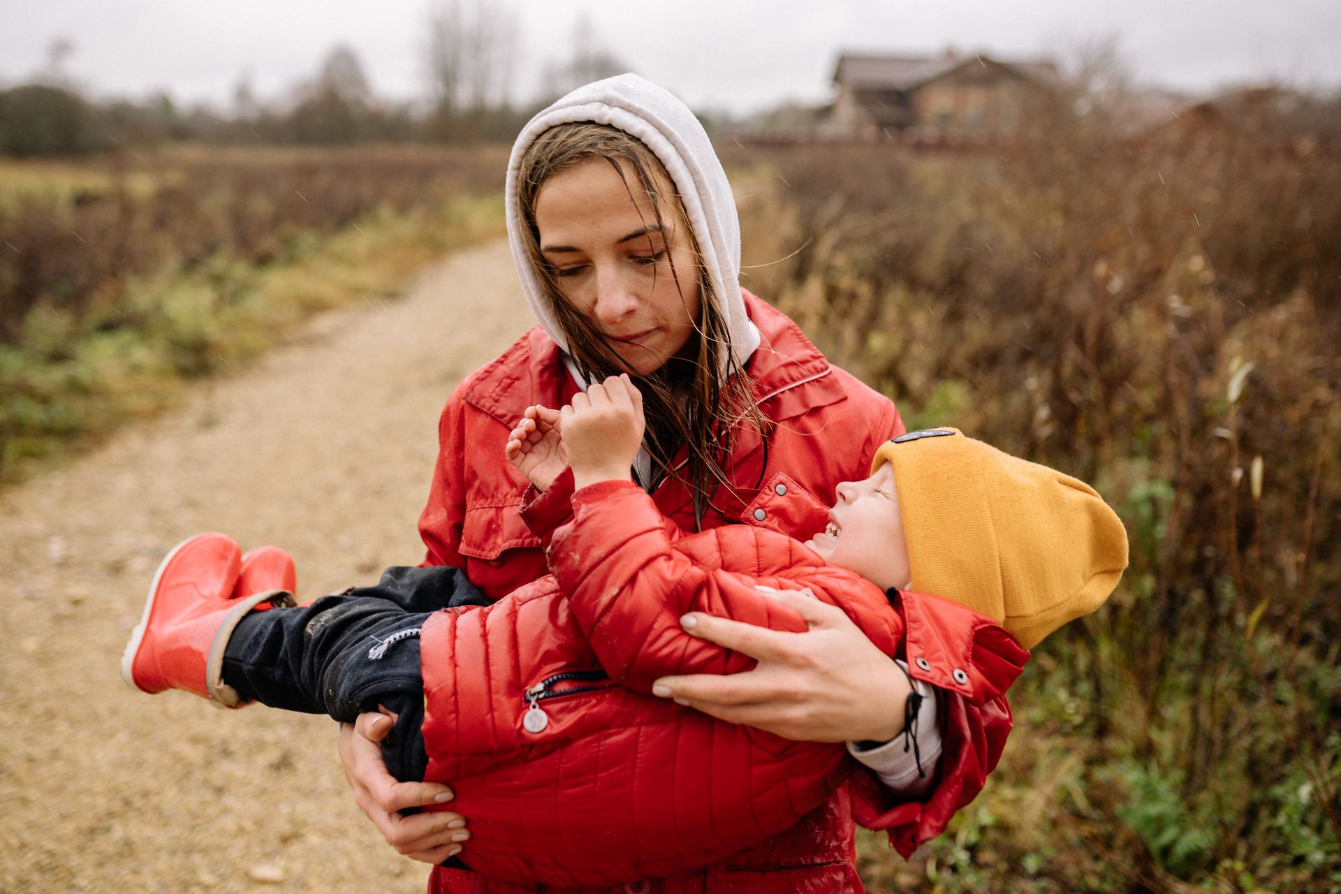 Woman in Red and Black Jacket Carrying Child in Red Jacket
