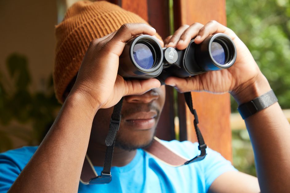 Homeowner using binoculars from ground level to inspect roof and gutters Homeowner using binoculars from ground level to inspect roof and gutters
