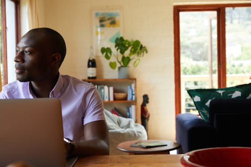 Thoughtful black man with laptop at home