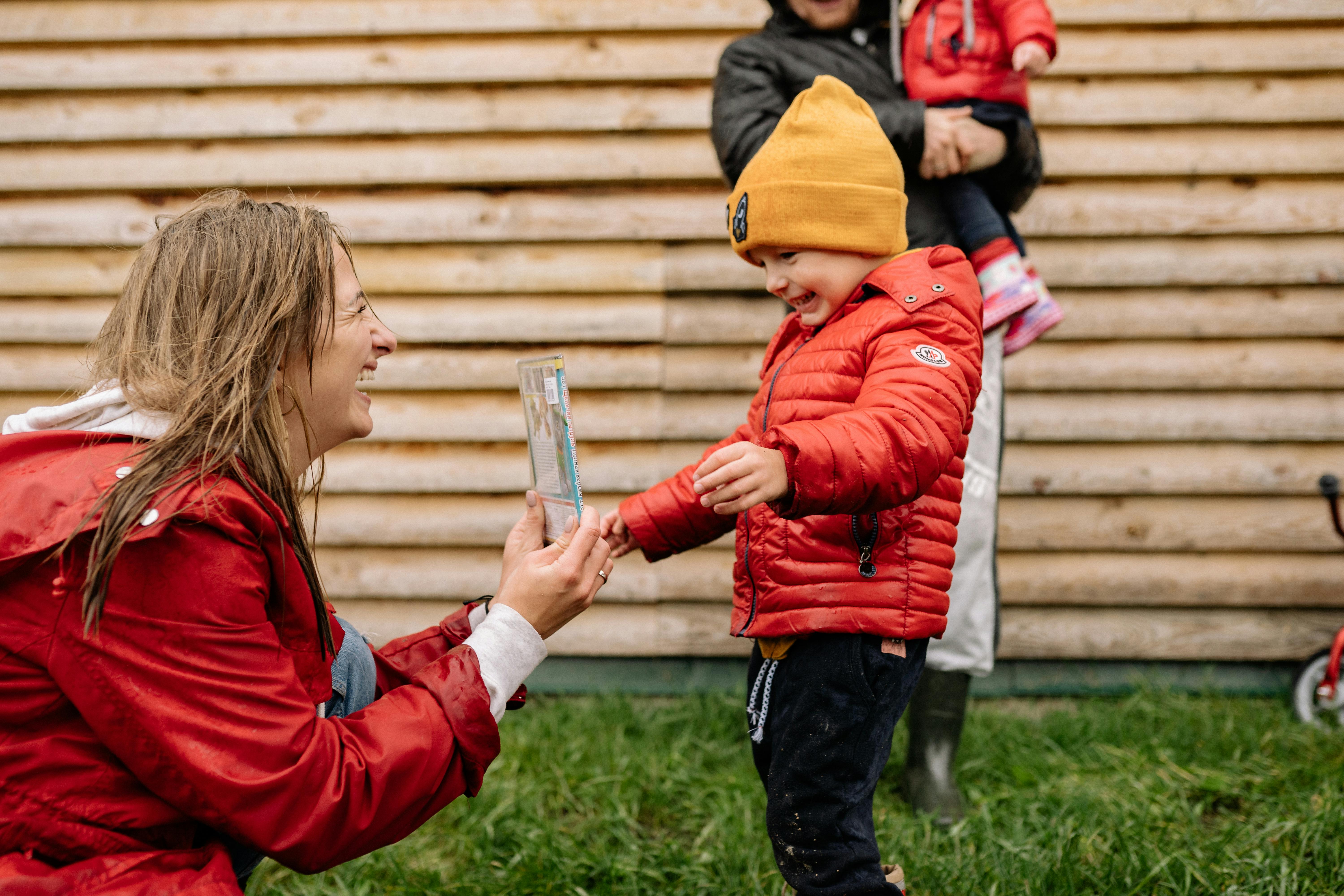 Smiling family enjoying a playful moment outdoors with children in colorful jackets.