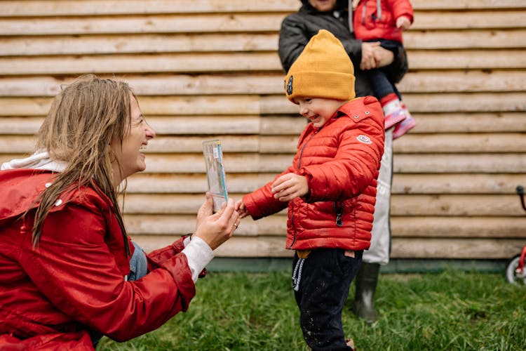 Woman In Red Jacket Smiling In Front Of A Child In Red Jacket