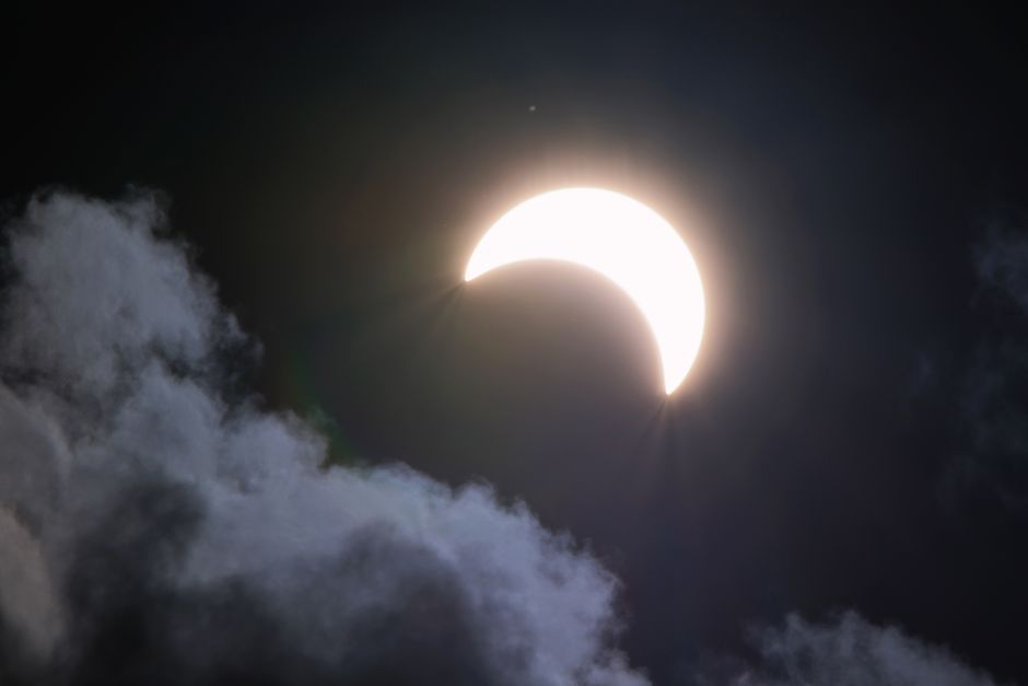Fotomural Una brillante luna creciente parcialmente oculta por nubes por la noche, creando una escena celestial dramática.
