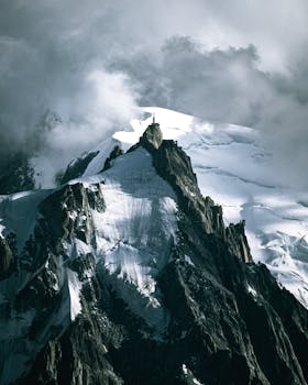 Dramatic view of snow-covered peaks and cloudy skies in Chamonix-Mont-Blanc.