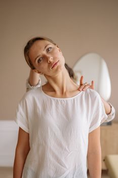 A woman in a white shirt receives a gentle neck stretch from a therapist indoors. — photo by Yan Krukau