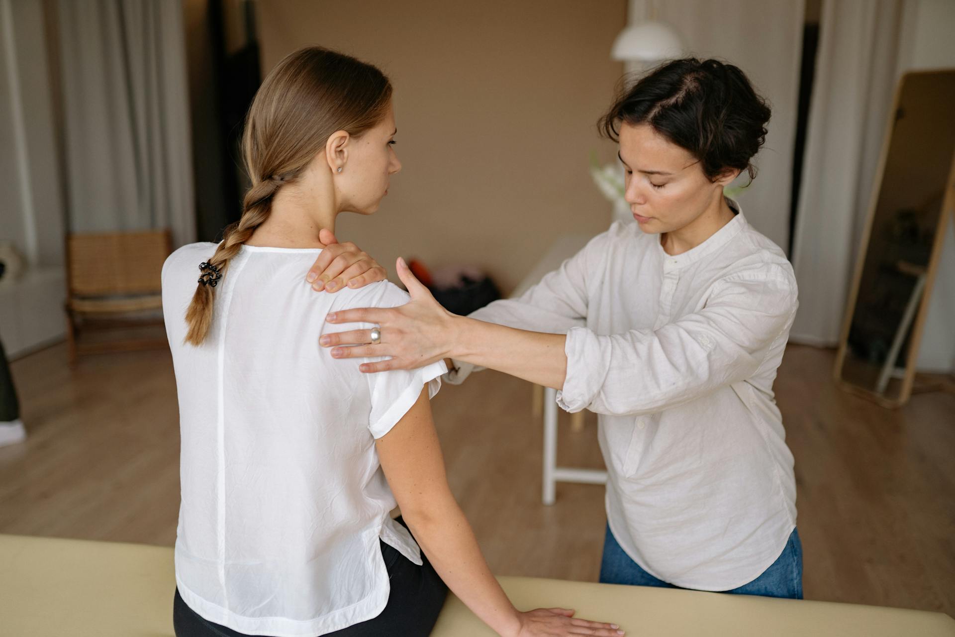 A therapist performing a shoulder massage on a woman to relieve physical tension.