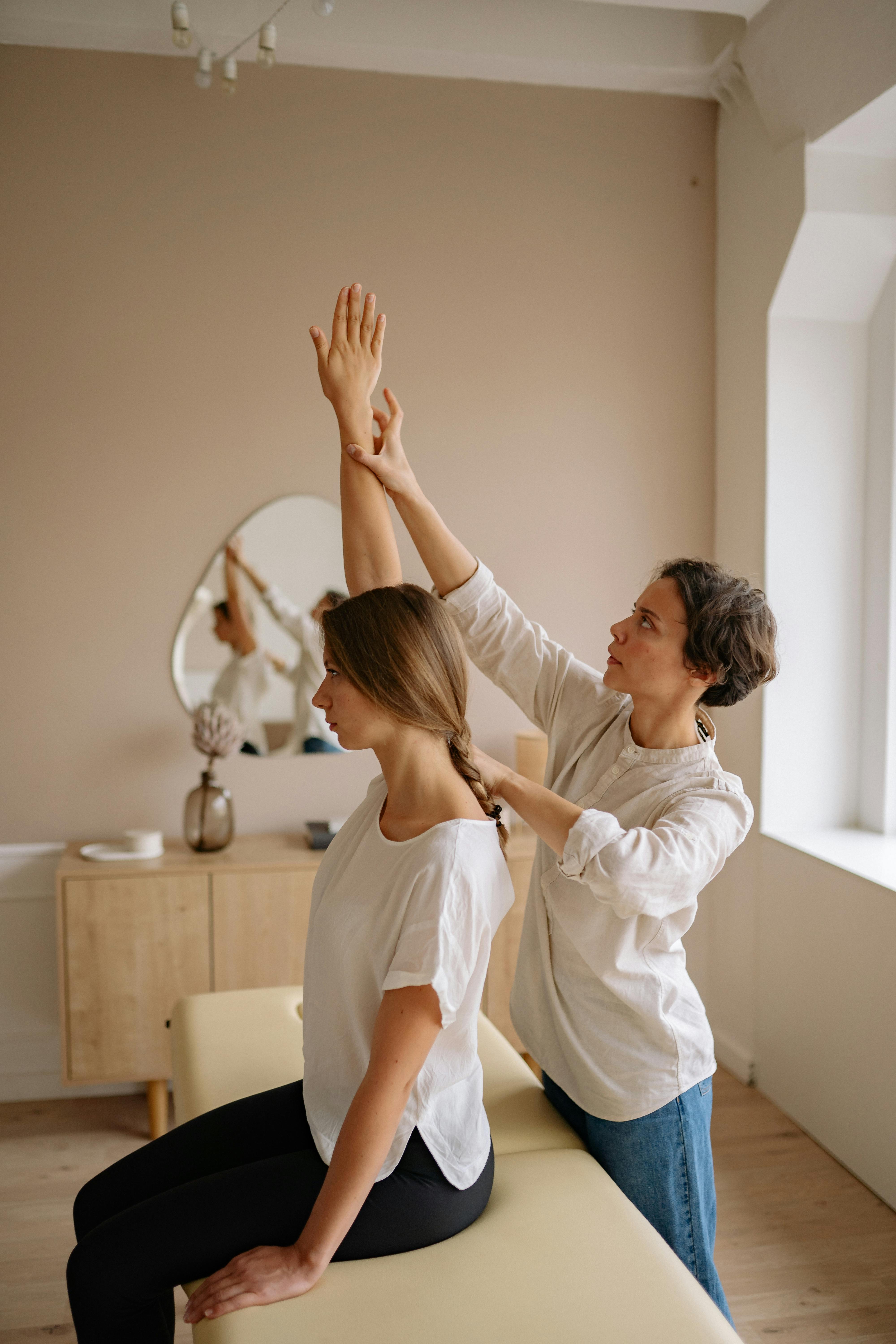 woman in white shirt sitting on white bed while raising her right hand