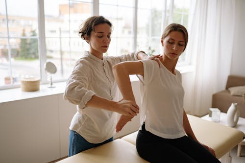Woman in White Long Sleeve Shirt Stretching Woman's Arm