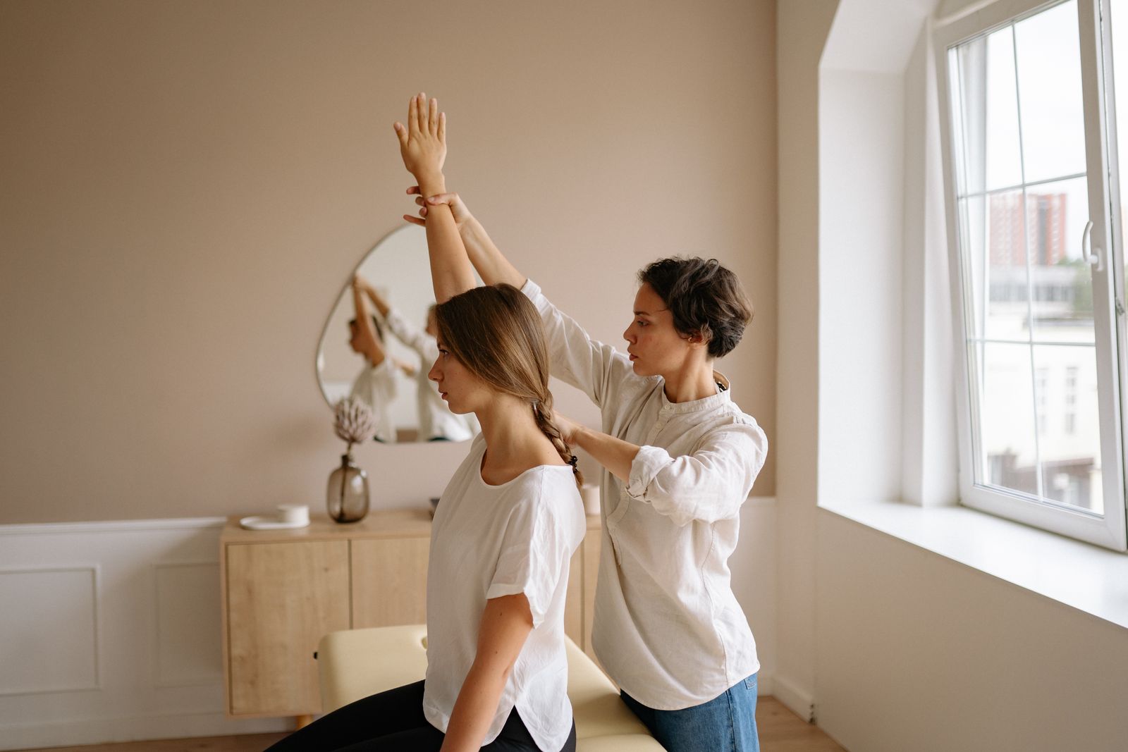Person adjusting a shoulder support during a bright physiotherapy session