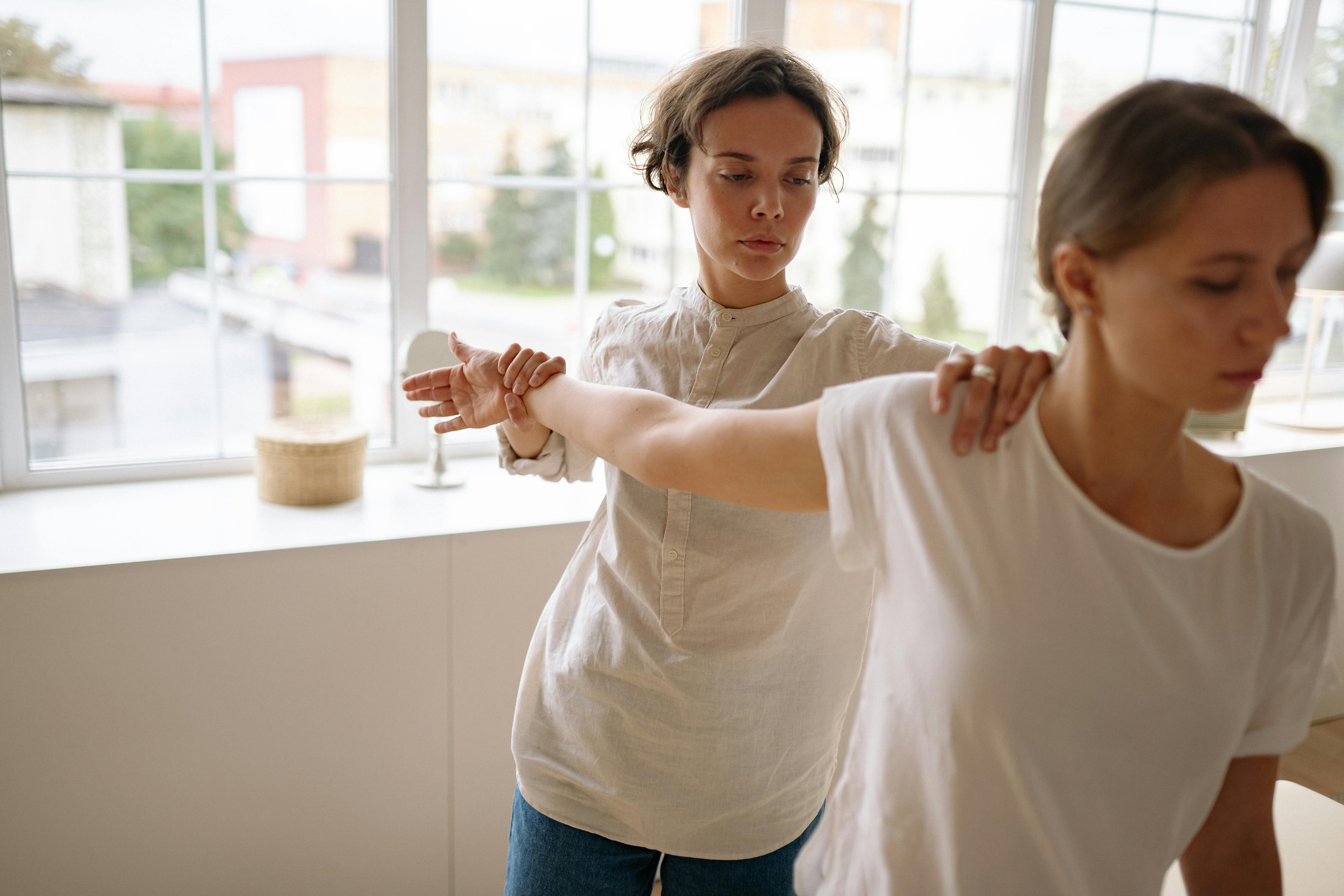 Therapist guiding a client through stretching exercises in a calm indoor setting.