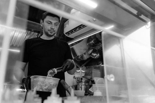 Free A chef prepares food in a professional kitchen, captured in monochrome for a classic look. Stock Photo