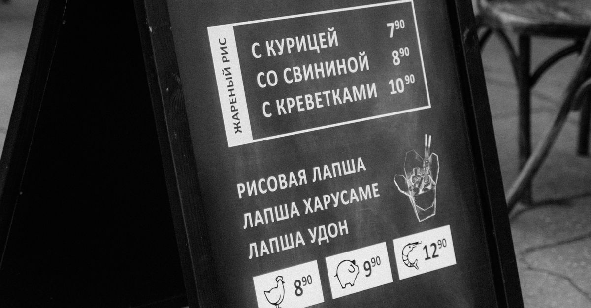 Monochrome photo of a restaurant menu board outdoors showcasing various dishes.