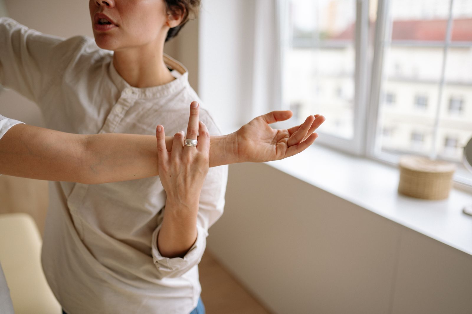 Person measuring their elbow and forearm for brace sizing at a bright table