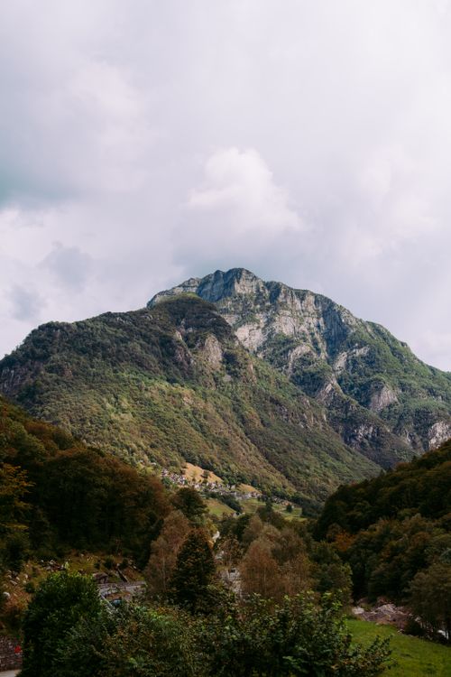 Free Picturesque scenery of mountain ridge with green trees and bushes in highland valley under clouds Stock Photo