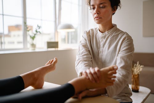 A Woman Massaging a Client's Foot