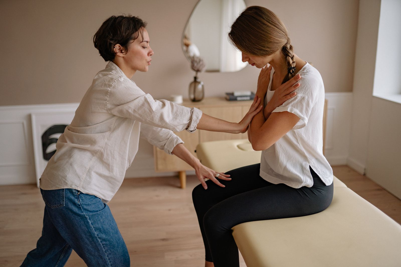Chiropractor assessing upper back and shoulder posture in a bright clinic
