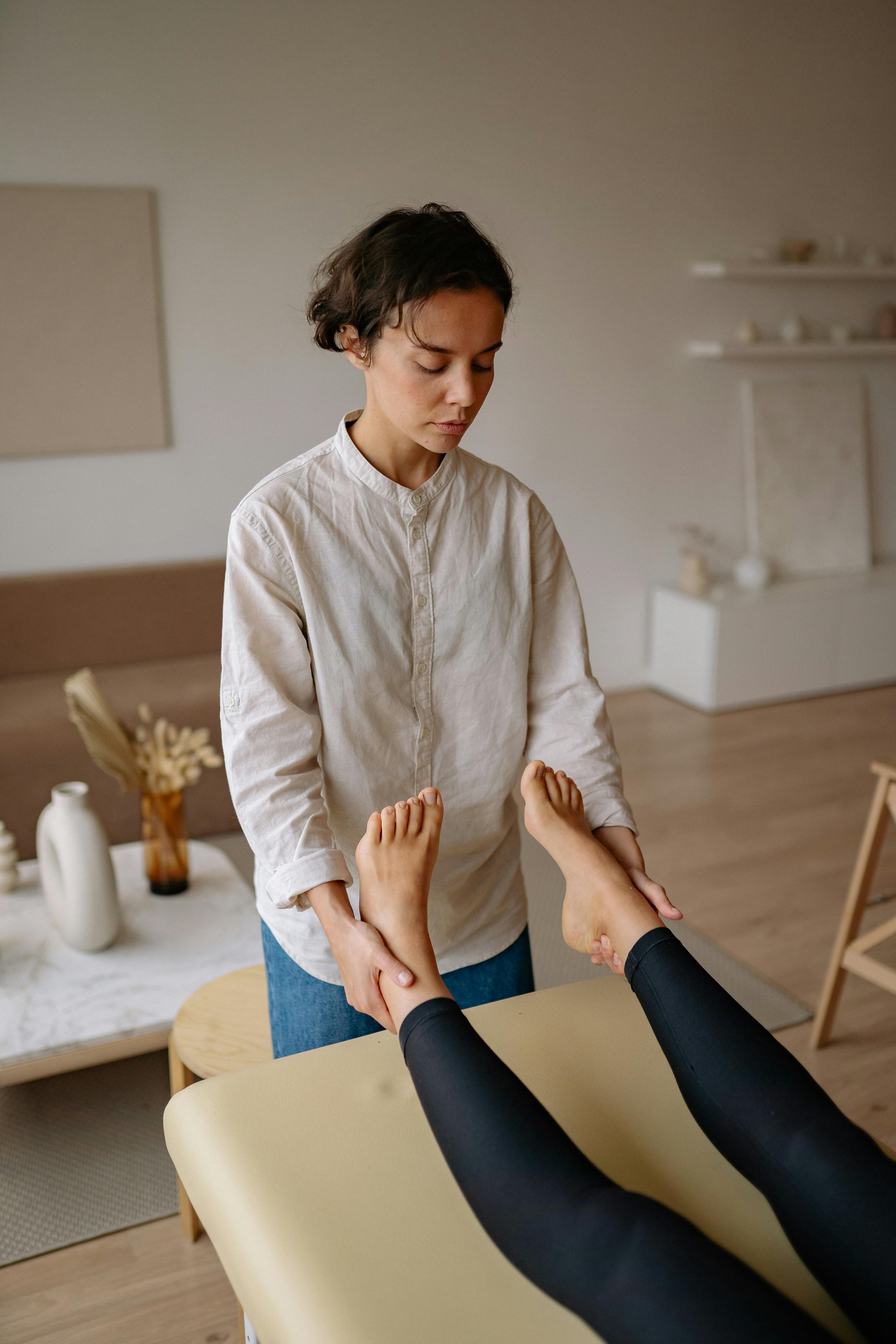 a massage therapist holding patient s feet while lying on therapy bed