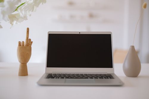 Free A minimalist workspace featuring a laptop with decorative items and floral arrangement. Stock Photo