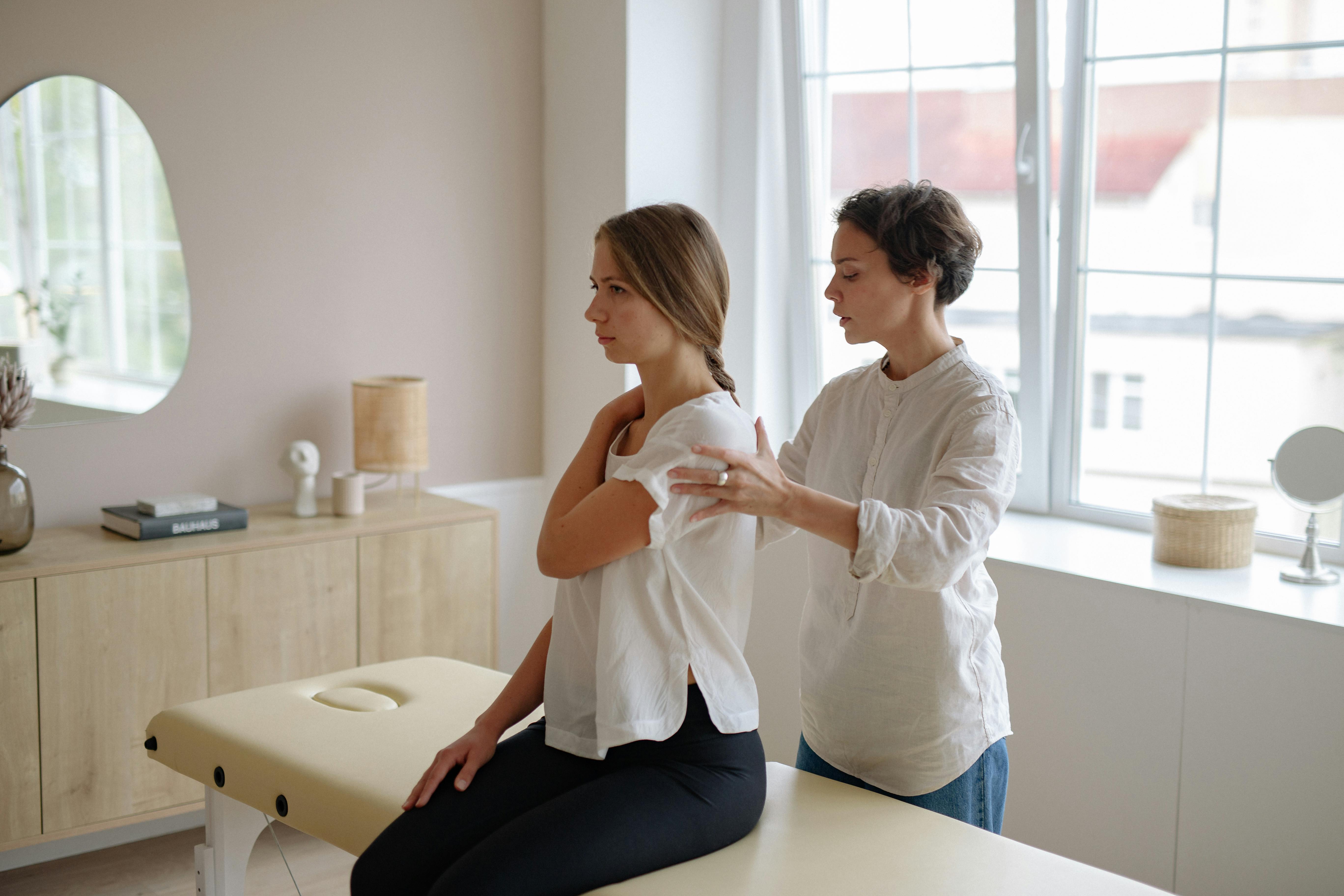 a massage therapist holding a woman s shoulder