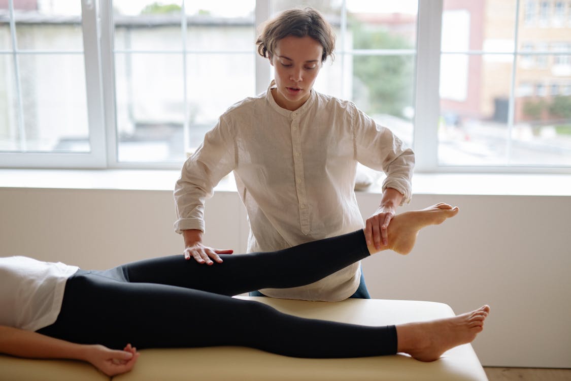 Free Woman in White Dress Shirt Holding a Person's Legs Stock Photo