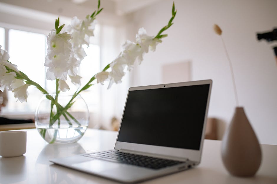 Ultimate Smart Light Switch Installation Guide (2025) A minimalist workspace with a silver laptop and white flowers in a vase on a table.